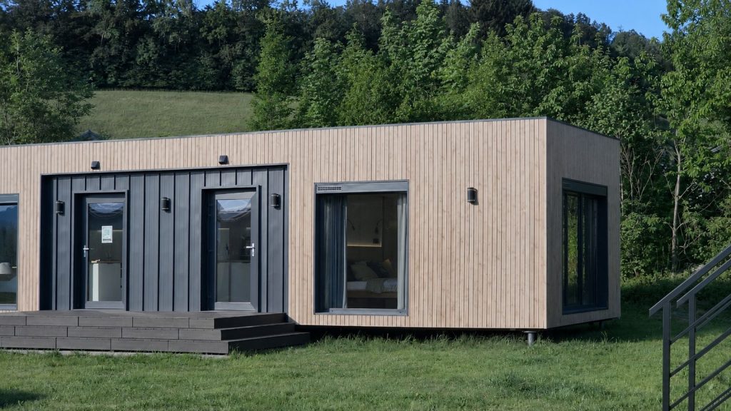 Alpenchalet mit heller Holzfassade und Terrasse als Premium-Modulhaus, Lieferung in die Steiermark.