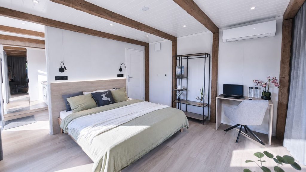 Helles Schlafzimmer im Alpenchalet mit Holzbalken, Doppelbett und Arbeitsplatz - Fertighaus, Lieferung nach Graz.