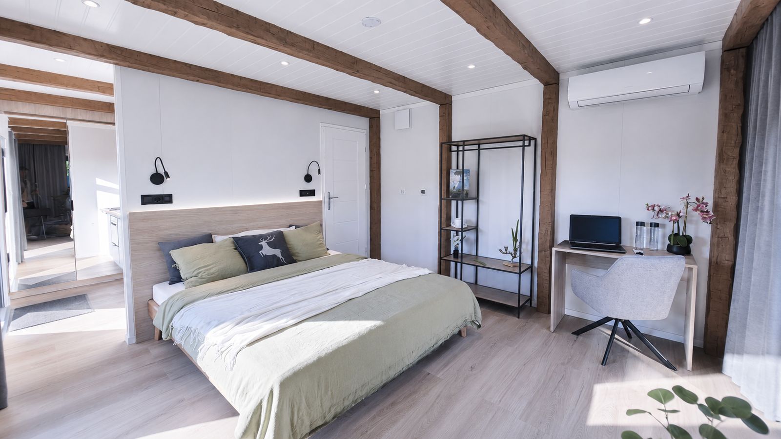 Helles Schlafzimmer im Alpenchalet mit Holzbalken, Doppelbett und Arbeitsplatz - Fertighaus, Lieferung nach Graz.