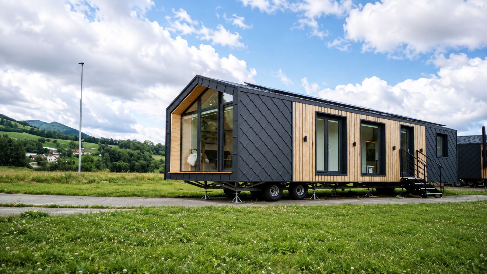 Diamond Family Deluxe mit anthrazit Rautenfassade, Holzverkleidung und Giebelverglasung auf gruener Wiese - Ganzjahreshaus.