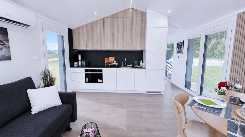 Offener Wohn-Ess-Kochbereich im Premium-Modulhaus Diamond Family Deluxe mit Holzfronten und Bergblick - lieferbar nach Linz.