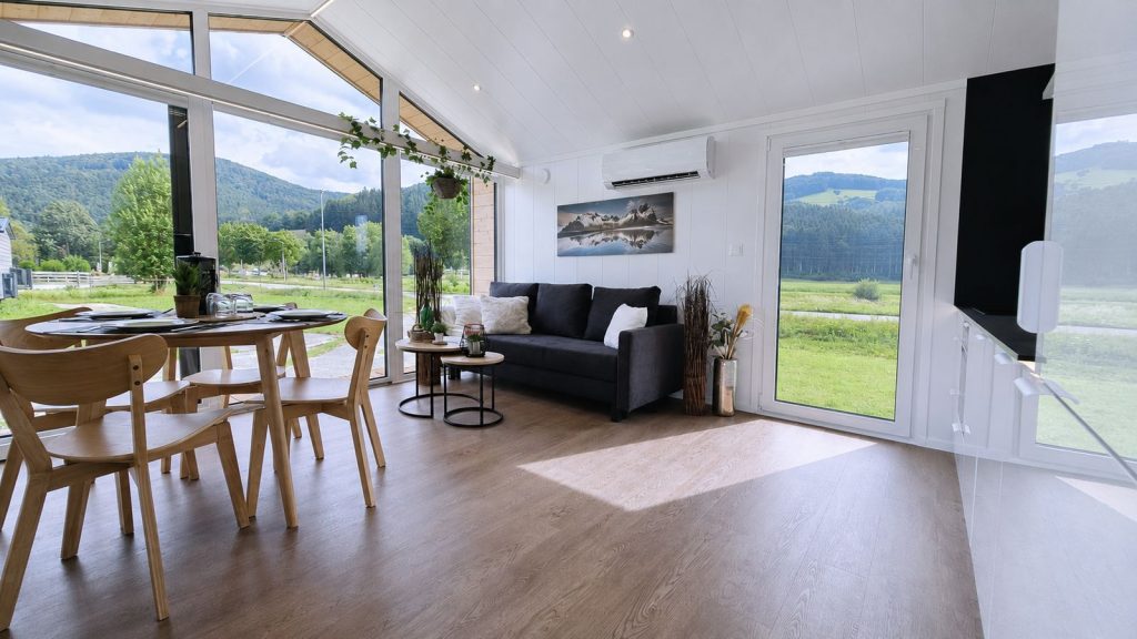 Wohn-Essbereich mit Panoramafenstern, Holzstühlen und dunklem Sofa - modernes Eigenheim, verfügbar in Innsbruck.