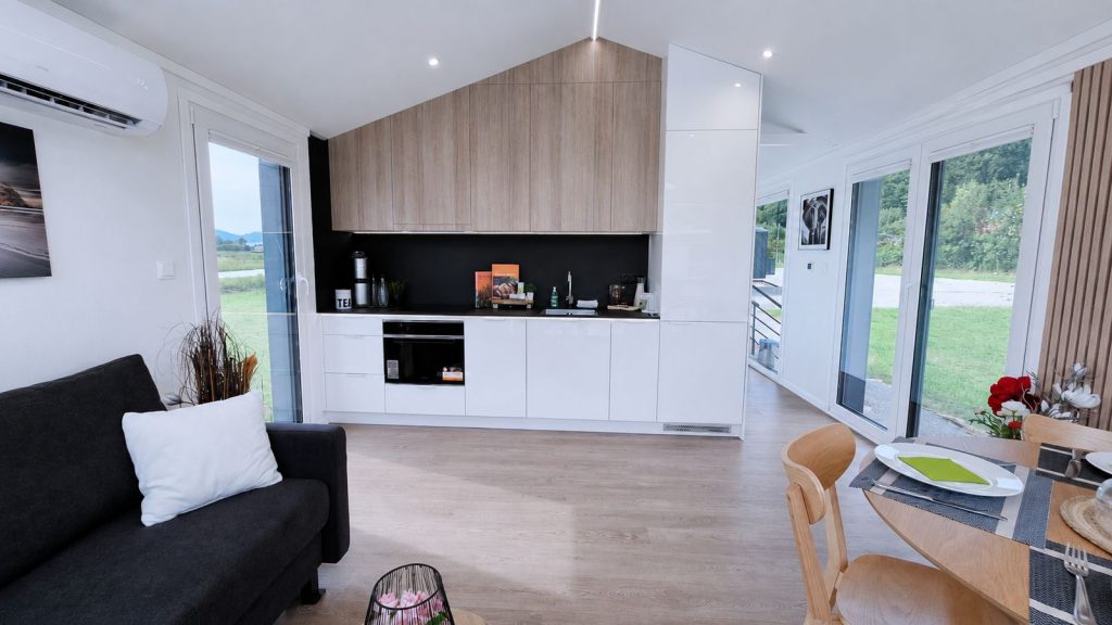 Offener Koch- und Wohnbereich mit Holzkueche und Schiebetueren in durchdachter Massivmodul-Architektur.