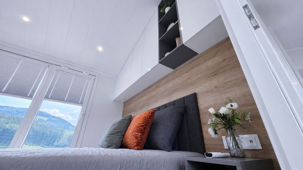Schlafzimmer im Diamond Family Deluxe mit Holzwand, gepolstertem Kopfteil und Hügelblick, vollmöbliert und verfügbar in Salzburg.