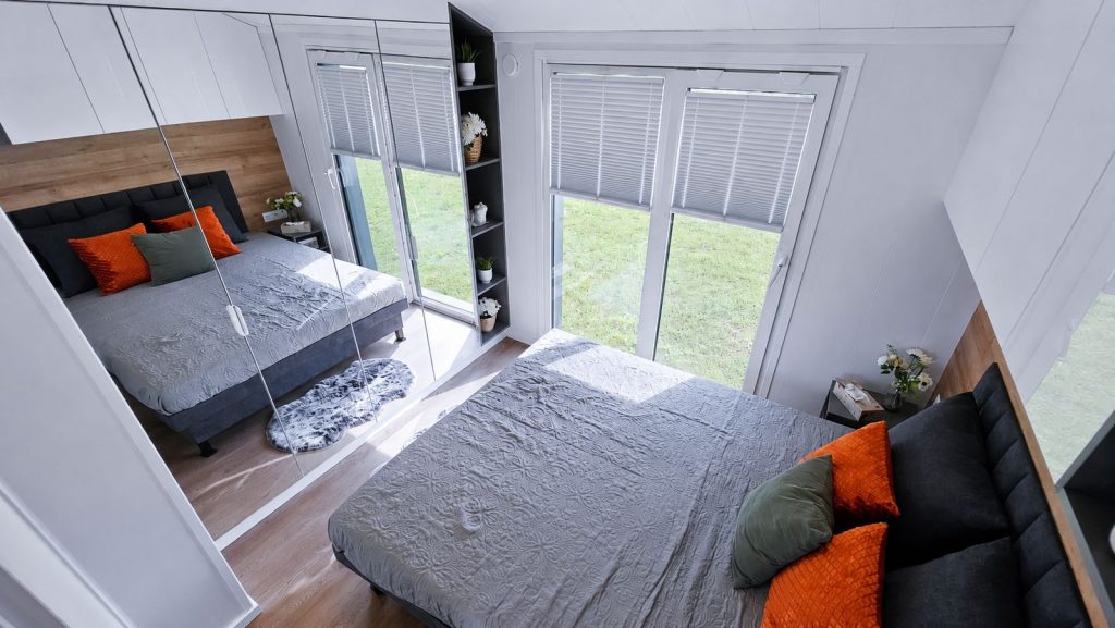 Vollmoebliertes Schlafzimmer mit Spiegelschrank, grauer Tagesdecke und farbigen Kissen, Lieferung nach Innsbruck.