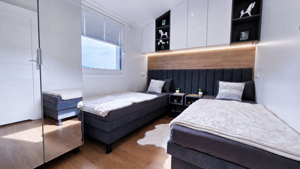 Kinderzimmer mit zwei Einzelbetten, Holz-Rückwand und Spiegelschrank im Modulhaus - Lieferung nach Klagenfurt.