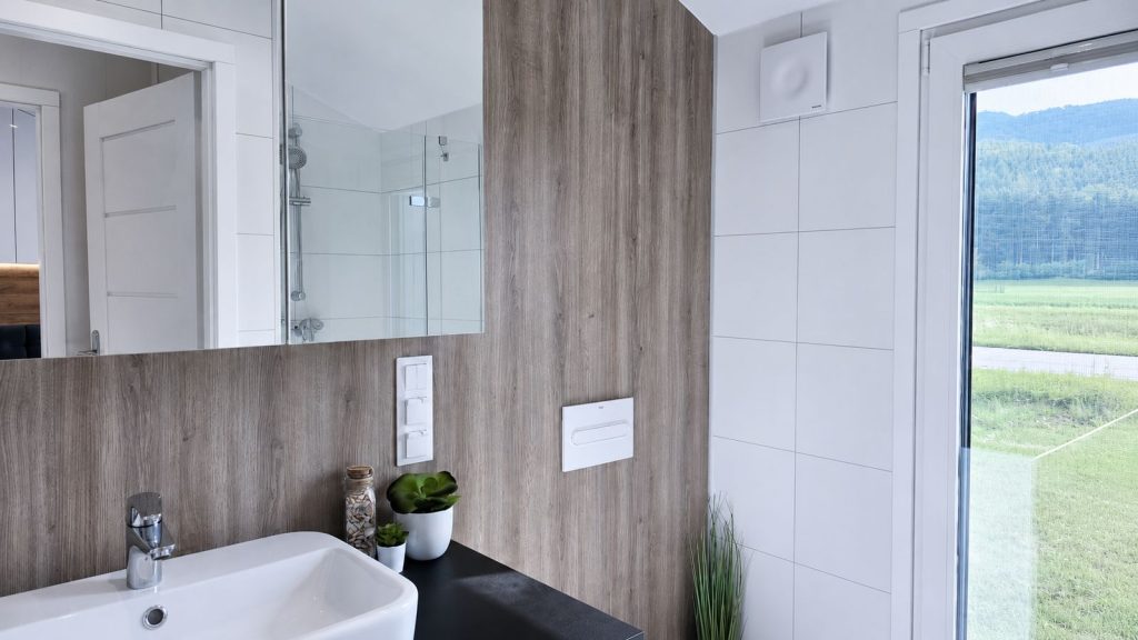 Badezimmerdetail im Fertighaus Diamond Family Deluxe mit Aufsatzwaschbecken, Holzwand und Fensterblick - lieferbar nach Wels.