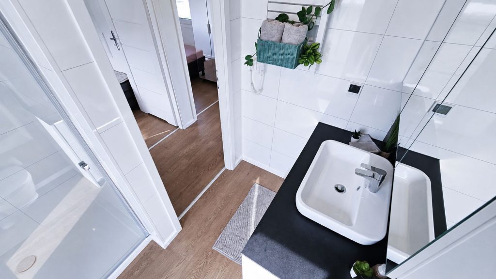 Badezimmer mit Dusche, schwarzem Waschtisch und Aufsatzbecken im Premium-Modulhaus - Lieferung nach Linz.