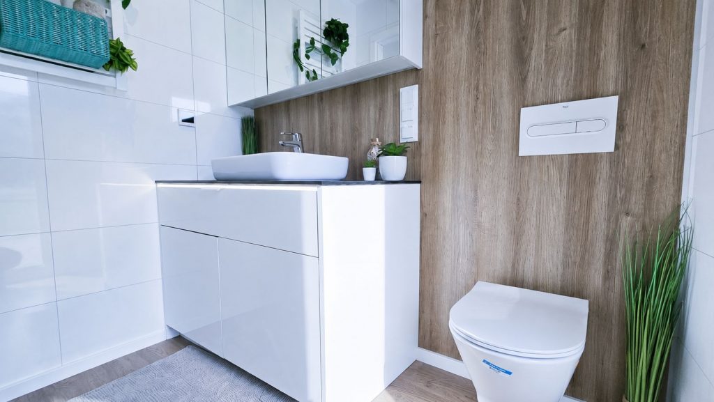 Bad im Diamond Family Deluxe mit weissem Hochglanzwaschtisch, Spiegelschrank und Haenge-WC an Holzoptik-Wand - schluesselfertig.