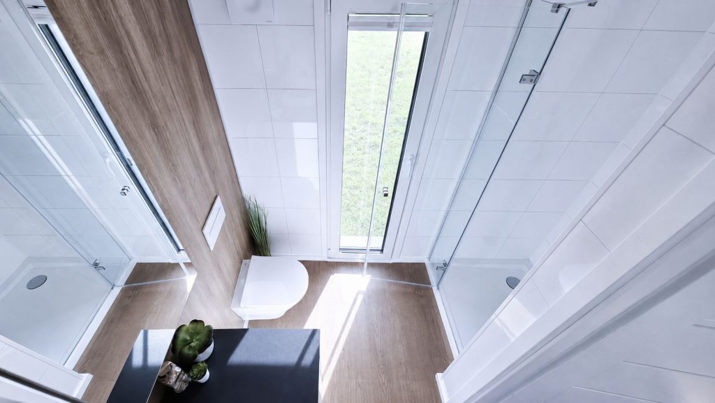 Helles Badezimmer mit zwei Duschkabinen und Tageslichtfenster im Fertigteilhaus, Lieferung nach Villach.