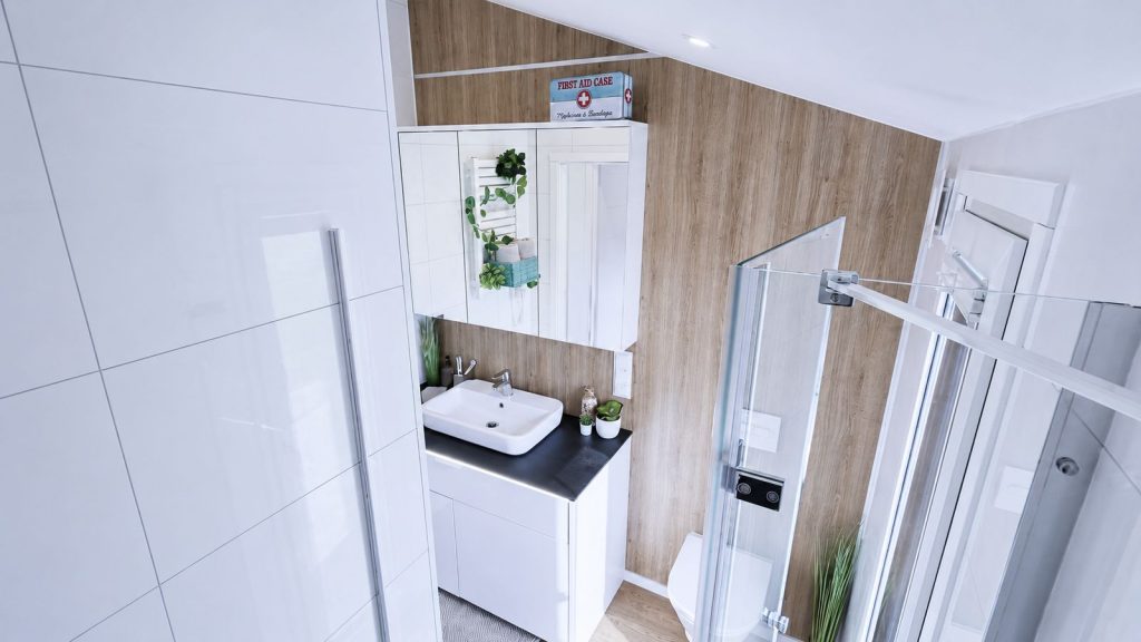 Schluesselfertiges Bad mit Waschtisch, Spiegelschrank und Glasdusche vor warmer Holzwand.