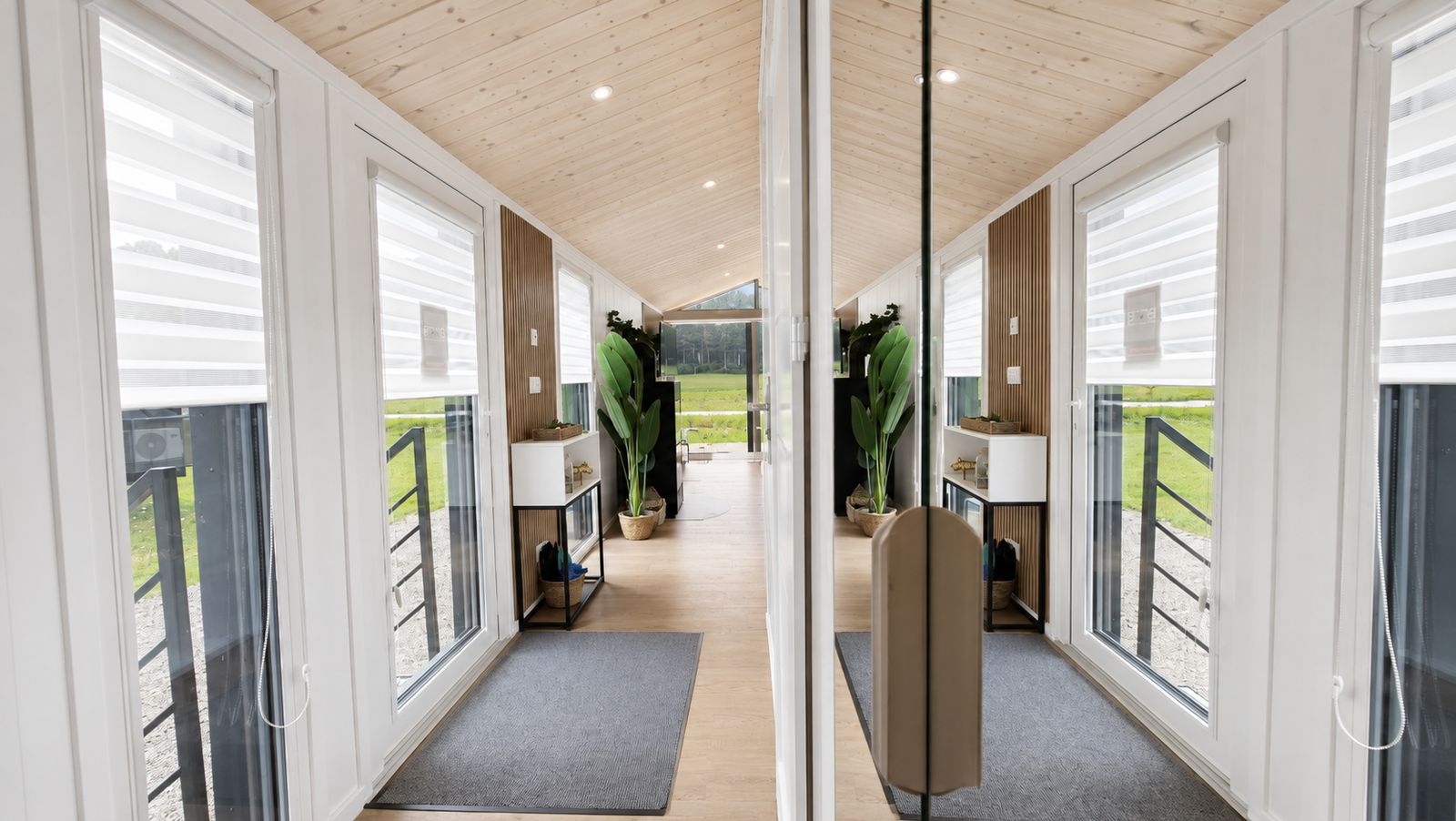 Heller Flur mit Holzdecke, bodentiefen Fenstern und Zimmerpflanze im Diamond +Plus Fertigteilhaus.
