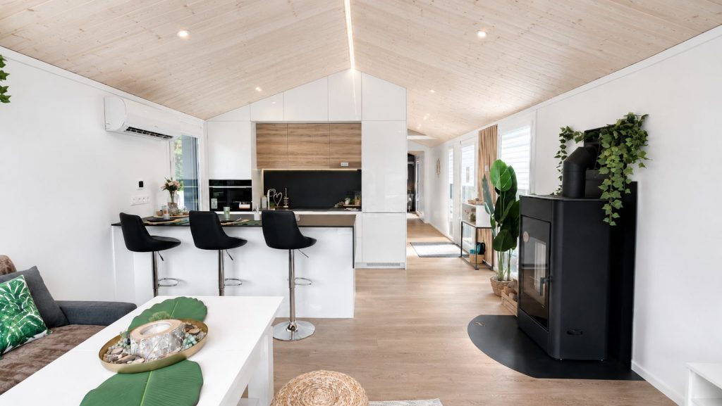 Wohnkueche mit Holzgiebeldecke, Bartresen und schwarzem Kaminofen im modernen Eigenheim - Lieferung nach Oberoesterreich.