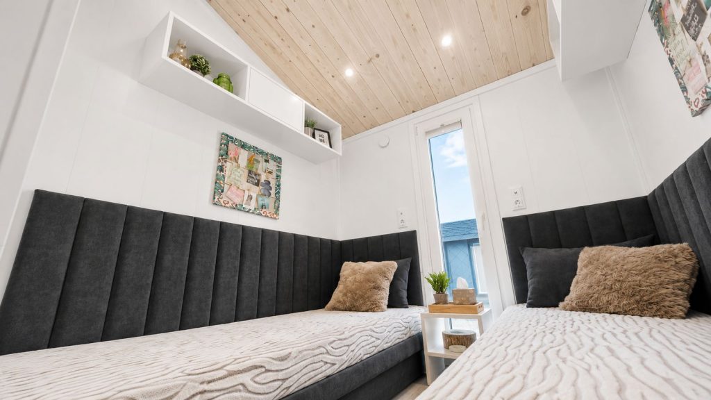 Kinderzimmer mit zwei Einzelbetten, dunklen Polsterhaeuptern und Holzdecke im Diamond +Plus - wohnfertig, Lieferung nach Salzburg.