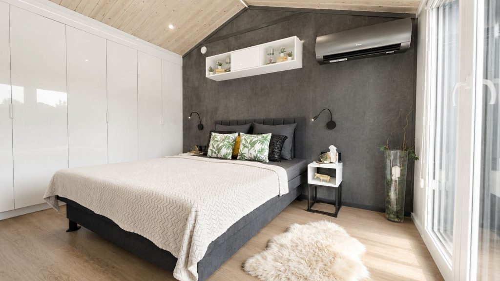 Modernes Schlafzimmer mit anthrazitfarbener Wand und Klimaanlage im Ganzjahreshaus, verfuegbar in Salzburg.
