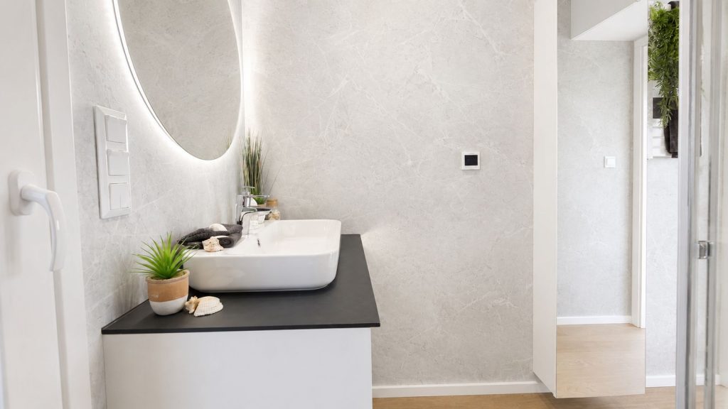 Gaeste-WC mit LED-Rundspiegel, Aufsatzwaschbecken und Marmoroptik - Fertighaus verfuegbar in der Steiermark.