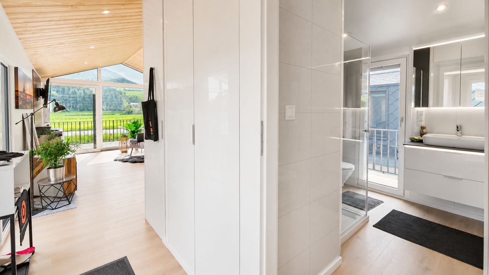 Durchblick vom Flur ins helle Wohnzimmer mit Panoramafenster und Bad - schlüsselfertig, verfügbar in Wien.