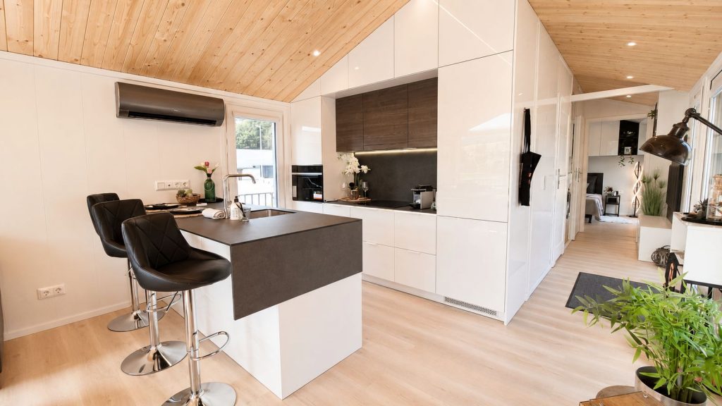 Offene Küche mit weißen Hochglanzfronten, Kochinsel und Holzdecke im Diamond +Plus Deluxe, modernes Eigenheim.