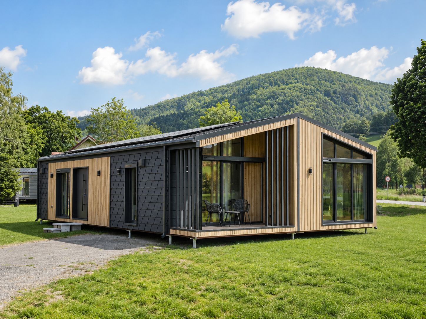 Diamond Vario Deluxe mit Holz- und Schieferfassade, Panoramagiebel und ueberdachter Terrasse - Premium-Modulhaus fuer Wels.
