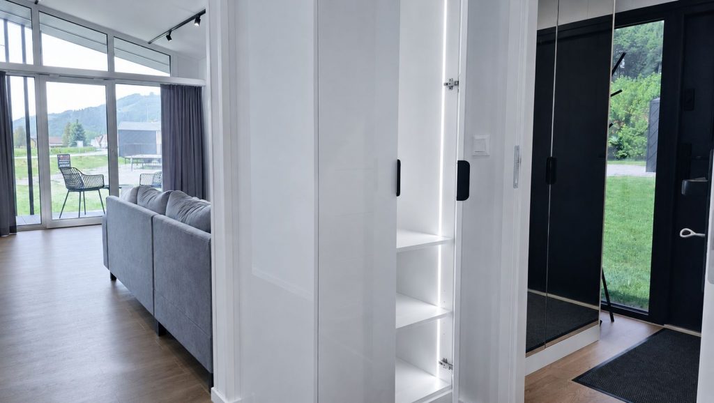 Eingangsbereich mit Garderobenschrank, Spiegelfront und Blick ins Wohnzimmer zur Terrasse - Ganzjahreshaus von BOND.