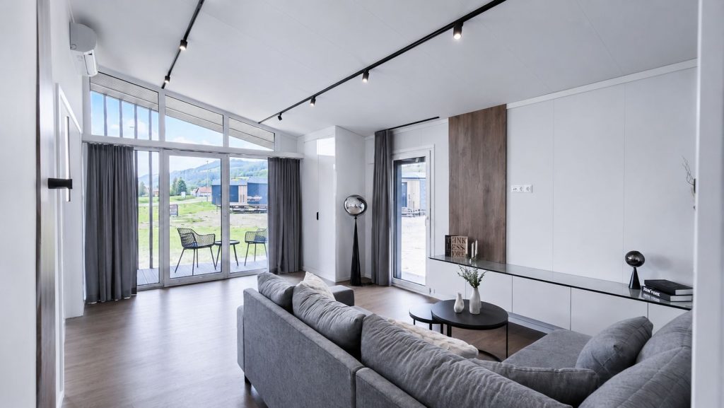 Lichtes Wohnzimmer mit grauem Ecksofa und Terrassenzugang im Diamond Vario Deluxe, modernes Eigenheim.