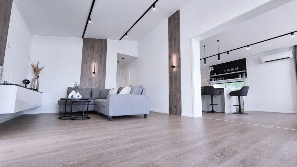 Grosszügiger Wohnraum im Diamond Vario Deluxe mit Eckcouch, Holzakzenten und Barbereich, Premium-Modulhaus für Wien.