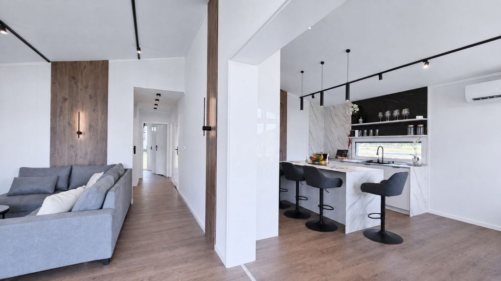 Diamond Vario Deluxe mit Sofa, Kuecheninsel in Marmoroptik und schwarzen Barhockern - modernes Eigenheim, verfuegbar in Villach.