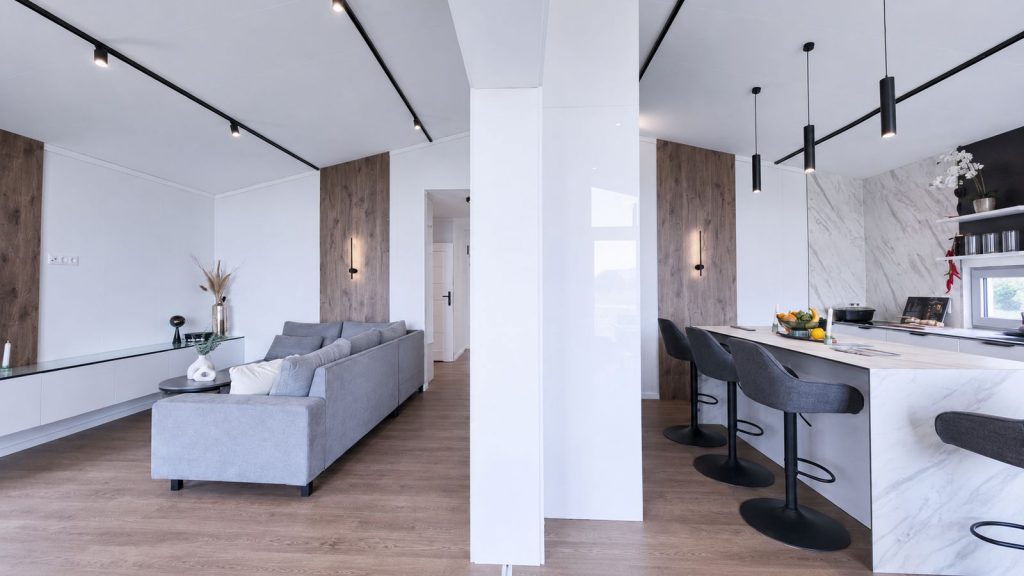 Vollmoeblierter Wohnraum im Diamond Vario Deluxe mit grauem Sofa, Marmor-Kuecheninsel und Barhockern.