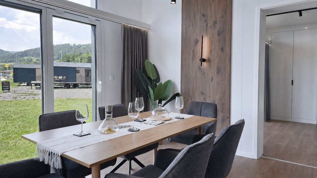 Essplatz mit Holztisch, gedeckten Gläsern und Holz-Akzentwand im Diamond Vario Deluxe, vollmöbliert übergeben.
