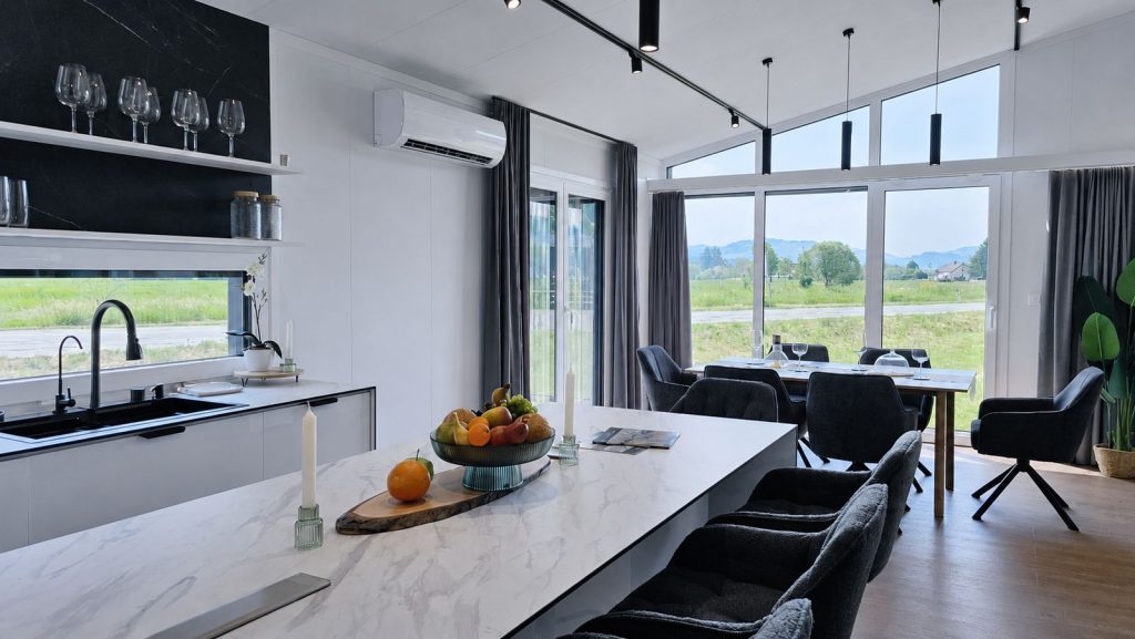 Kueche mit Marmorinsel, Obstschale und Panoramablick ins Gruene im Diamond Vario Deluxe Premium-Mobilheim.