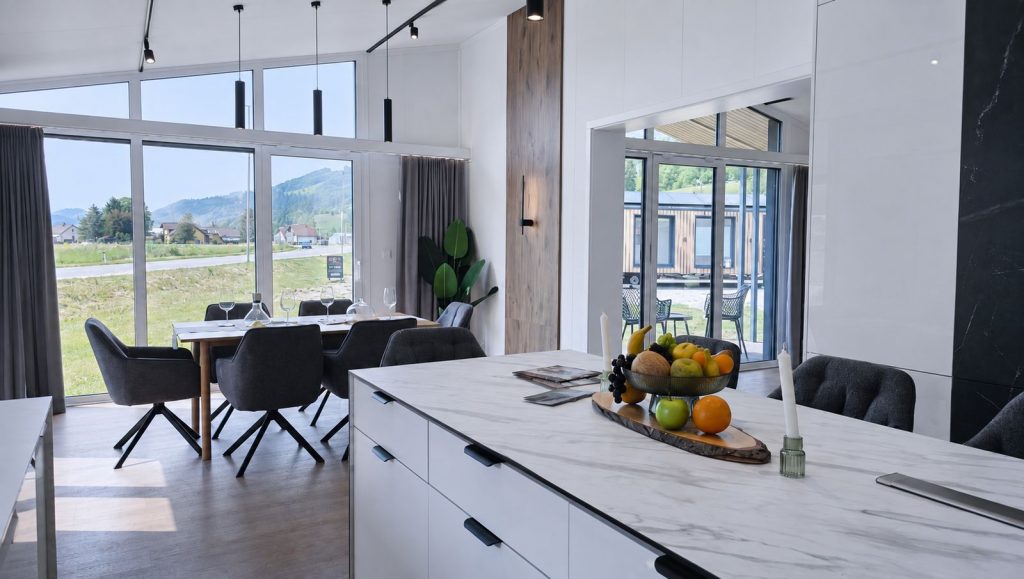 Diamond Vario Deluxe mit Marmor-Kueche und bodentiefen Fenstern zur Wiese, Premium-Modulhaus fuer Oberoesterreich.
