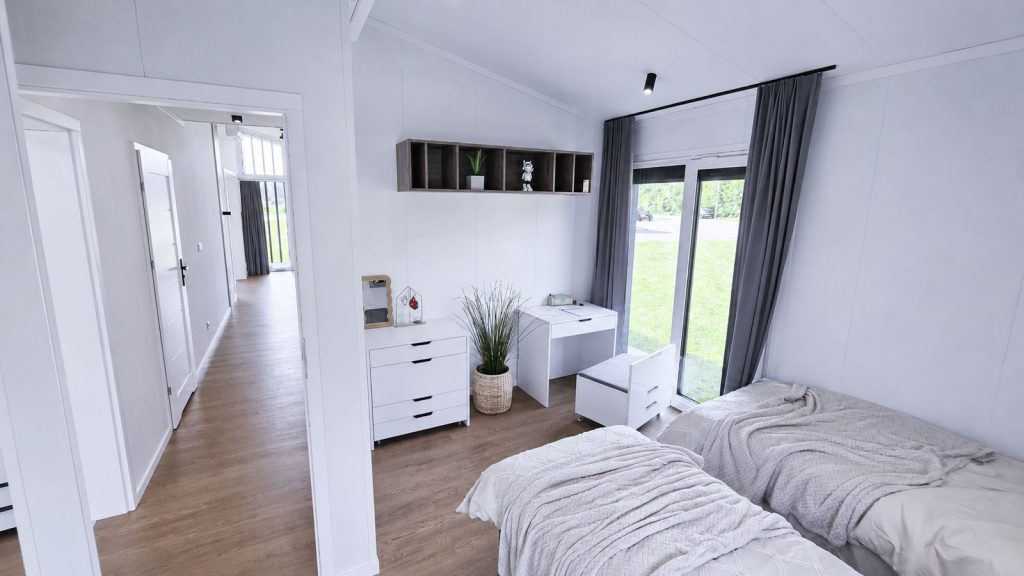 Zweites Schlafzimmer mit zwei Einzelbetten, Schreibtisch und Kommode sowie Gartenzugang - Fertigteilhaus fuer die ganze Familie.
