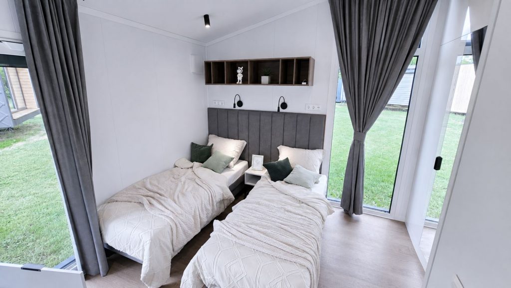 Zweibettzimmer mit gepolstertem Kopfteil und bodentiefen Fenstern - modernes Eigenheim fuer Tirol.