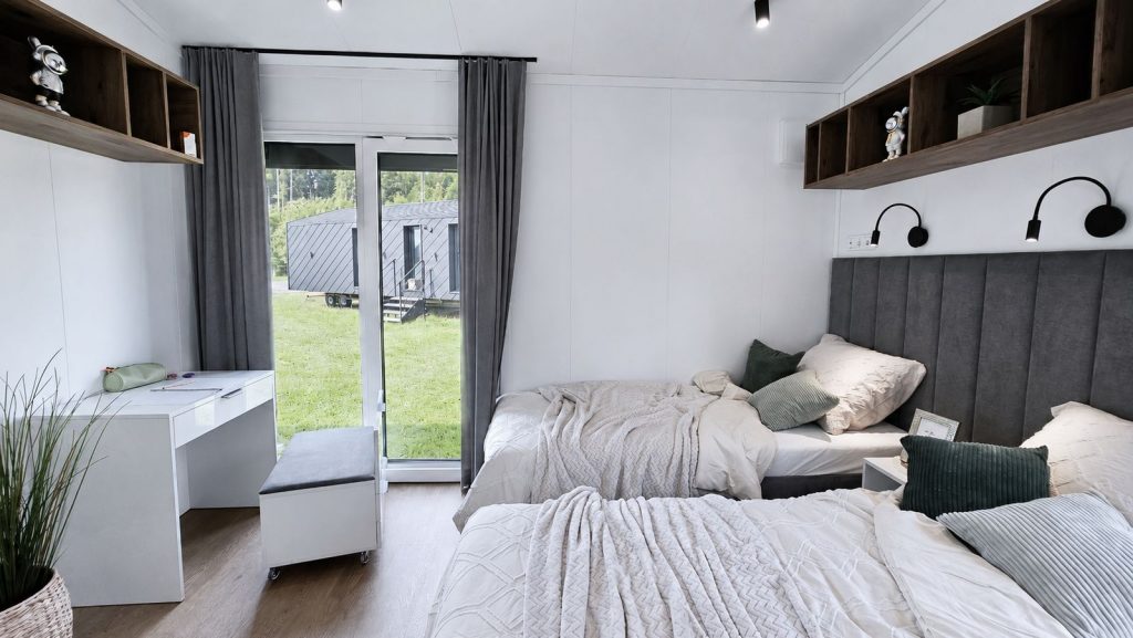 Vollmoebliertes Zweibettzimmer mit Leseleuchten, Schreibtisch und Gartentuer, ideal fuer Kinder oder Gaeste.