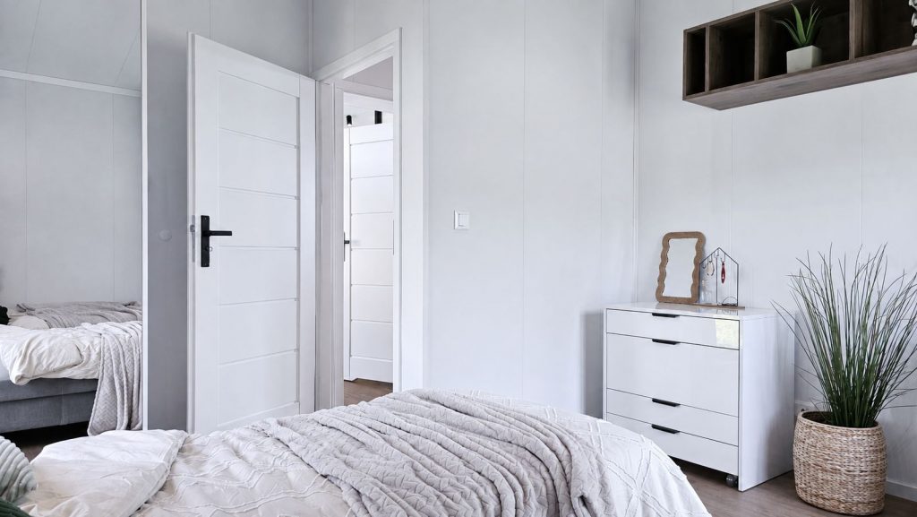 Schlafzimmer mit Doppelbett, weißer Kommode und Spiegelschrank im Diamond Vario Deluxe, schlüsselfertig.