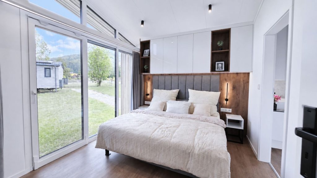 Schlafzimmer im Diamond Vario Deluxe mit Doppelbett, Holz-Kopfteil und bodentiefer Terrassentür, Ganzjahreshaus für Kärnten.