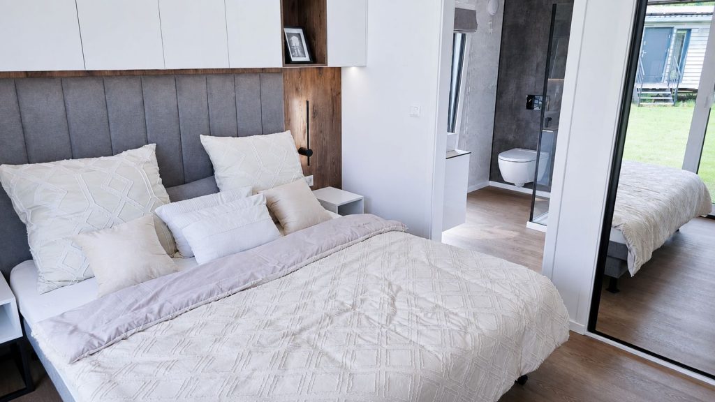 Schlafzimmer mit En-suite-Bad und Holzakzent als modernes Eigenheim, Lieferung nach Tirol.