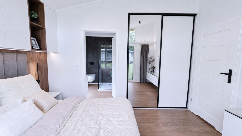 Schlafzimmer mit Spiegelkleiderschrank und Durchblick ins Ensuite-Bad im Modulhaus - Lieferung nach St. Pölten.