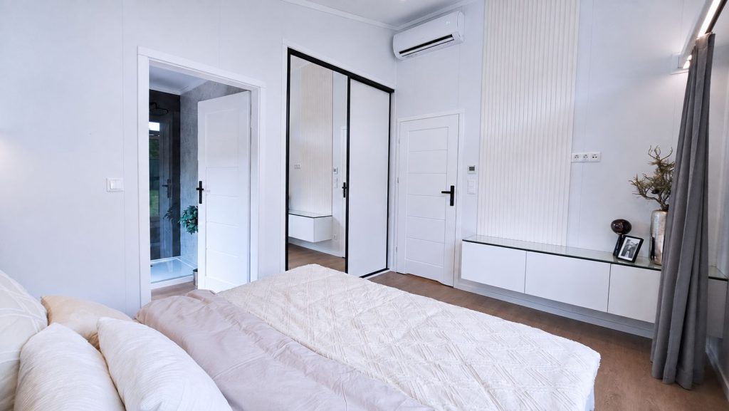 Schlafzimmer mit hellem Bett, Einbauschrank mit Spiegeltueren und offener Tuer zum Bad - vollmoebliert, Lieferung nach Steyr.