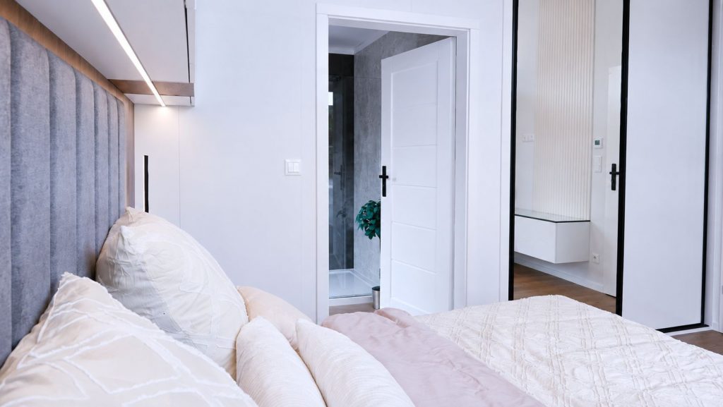 Wohnfertiges Schlafzimmer mit gepolstertem Kopfteil und Durchblick zum angrenzenden Ensuite-Badezimmer.