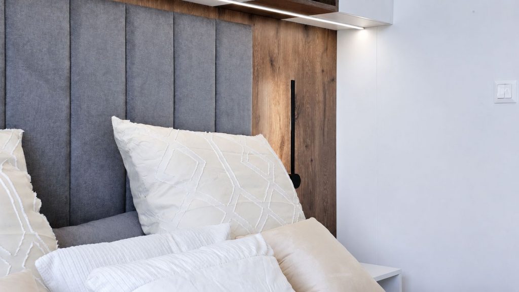 Detailaufnahme von Kissen, Polsterkopfteil und Holzpaneel im Diamond Vario Deluxe Premium-Modulhaus.