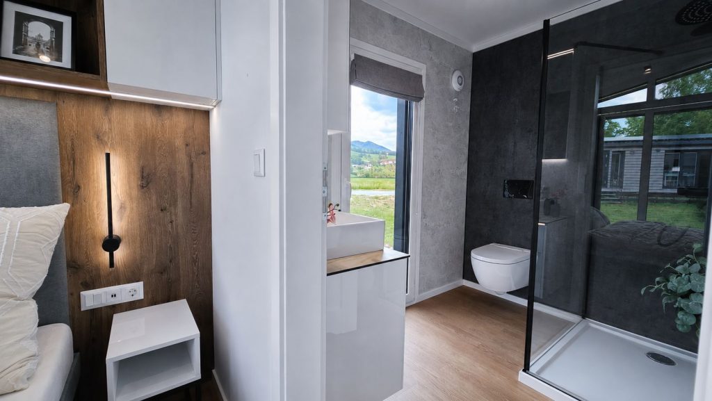 En-suite-Bad des Diamond Vario Deluxe mit Betonoptik, Wand-WC und Glasdusche, Massivmodul-Architektur fuer Vorarlberg.