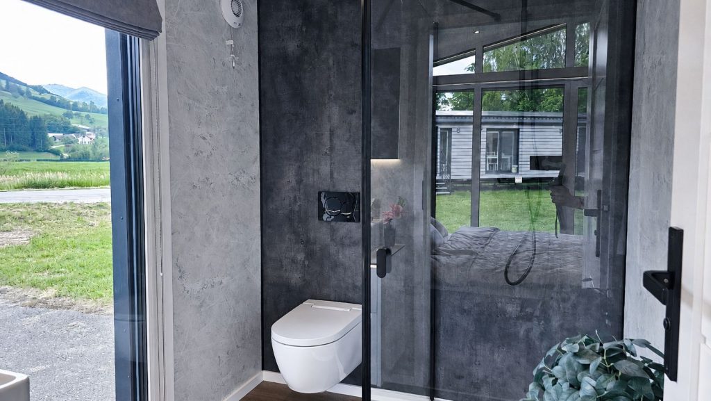 Ensuite-Bad im Premium-Mobilheim Diamond Vario Deluxe mit Betonoptik, Wand-WC und Panoramafenster - lieferbar nach Steyr.