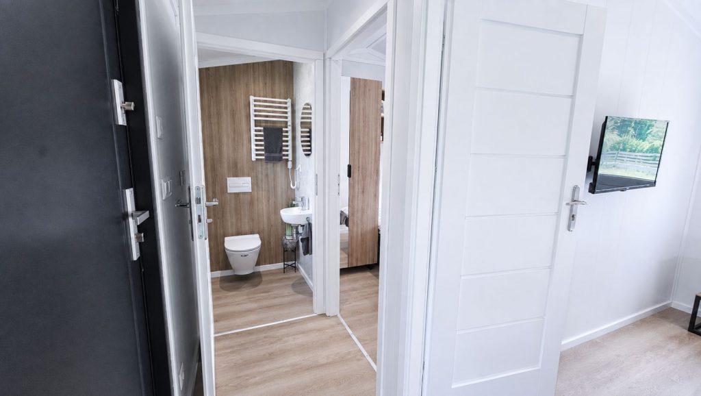 Wohnfertiger Flur im Quartier WSW mit Wand-TV und Durchblick in Gaeste-WC und Schlafraum.