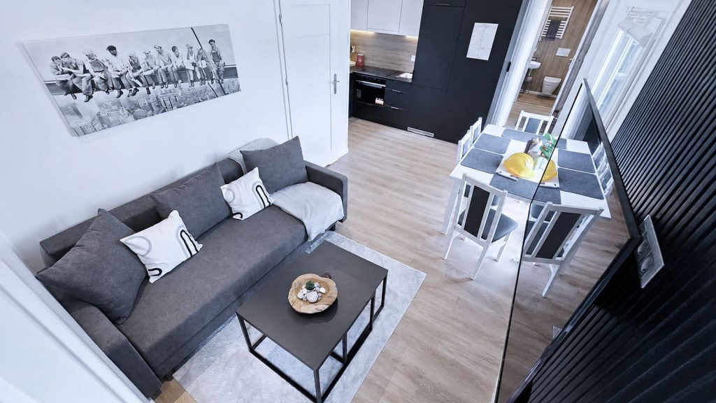 Wohn- und Essbereich im Quartier WSW mit Schlafsofa, Esstisch und schwarzer Kueche als kompaktes modernes Eigenheim.