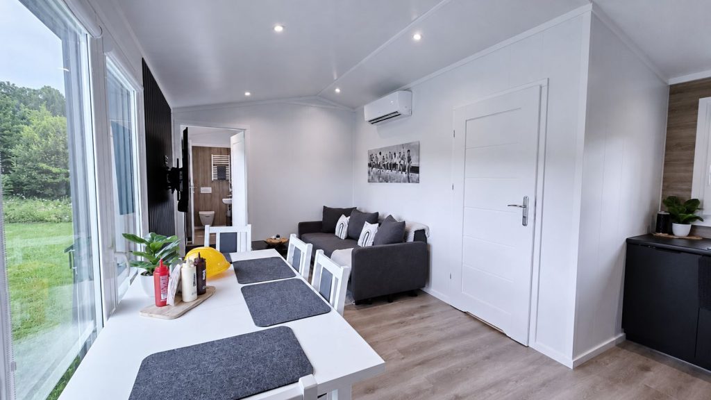 Wohn-Essbereich mit Sofa, Essplatz und Klimageraet, wohnfertig eingerichtet im robusten Modulbau von BOND.