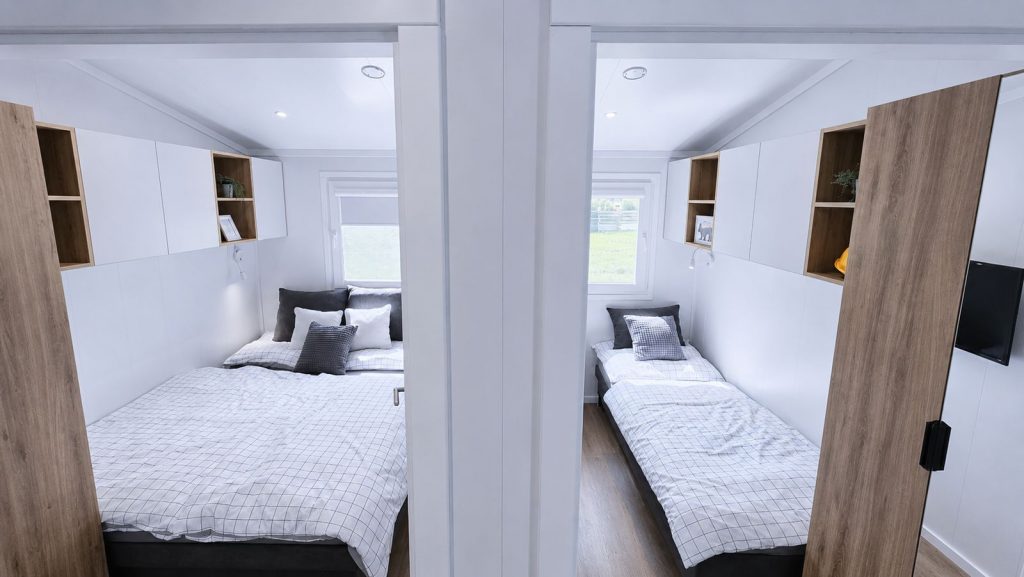 Zwei Schlafzimmer im Quartier WSW mit Doppel- und Einzelbett, weissen Schraenken und Holz-Regalwuerfeln.