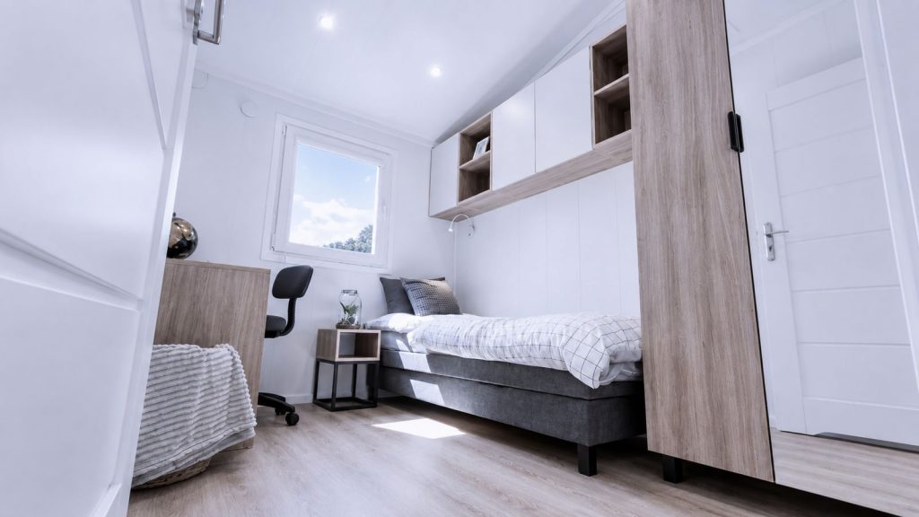 Kompaktes Schlafzimmer mit Einzelbett, Arbeitsplatz und Oberschraenken in Holzoptik - wohnfertig uebergeben.
