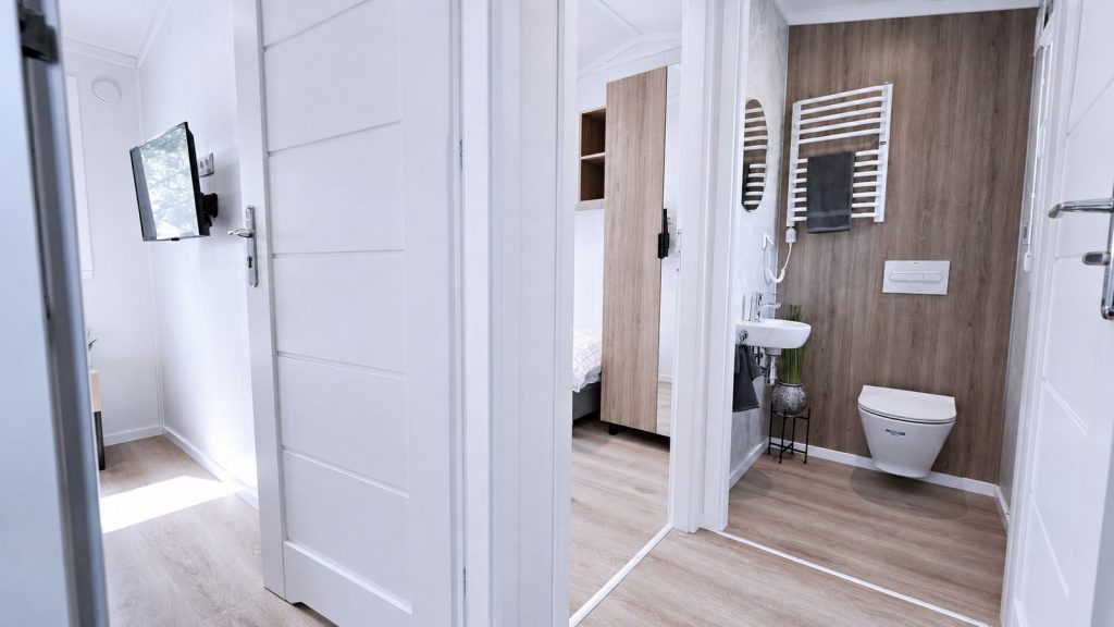Flur mit Blick auf Wand-WC, Holzoptik-Wand und angrenzendes Zimmer - schluesselfertig uebergeben.