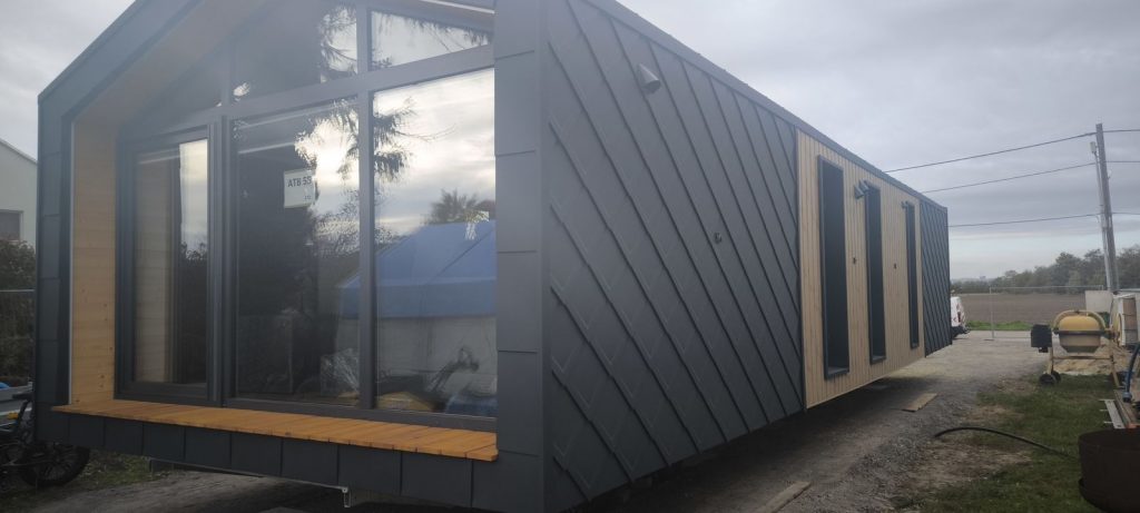 Außenansicht des schlüsselfertigen ATB 55 mit Glasfront, Holzelementen und langer anthrazitfarbener Rautenfassade.